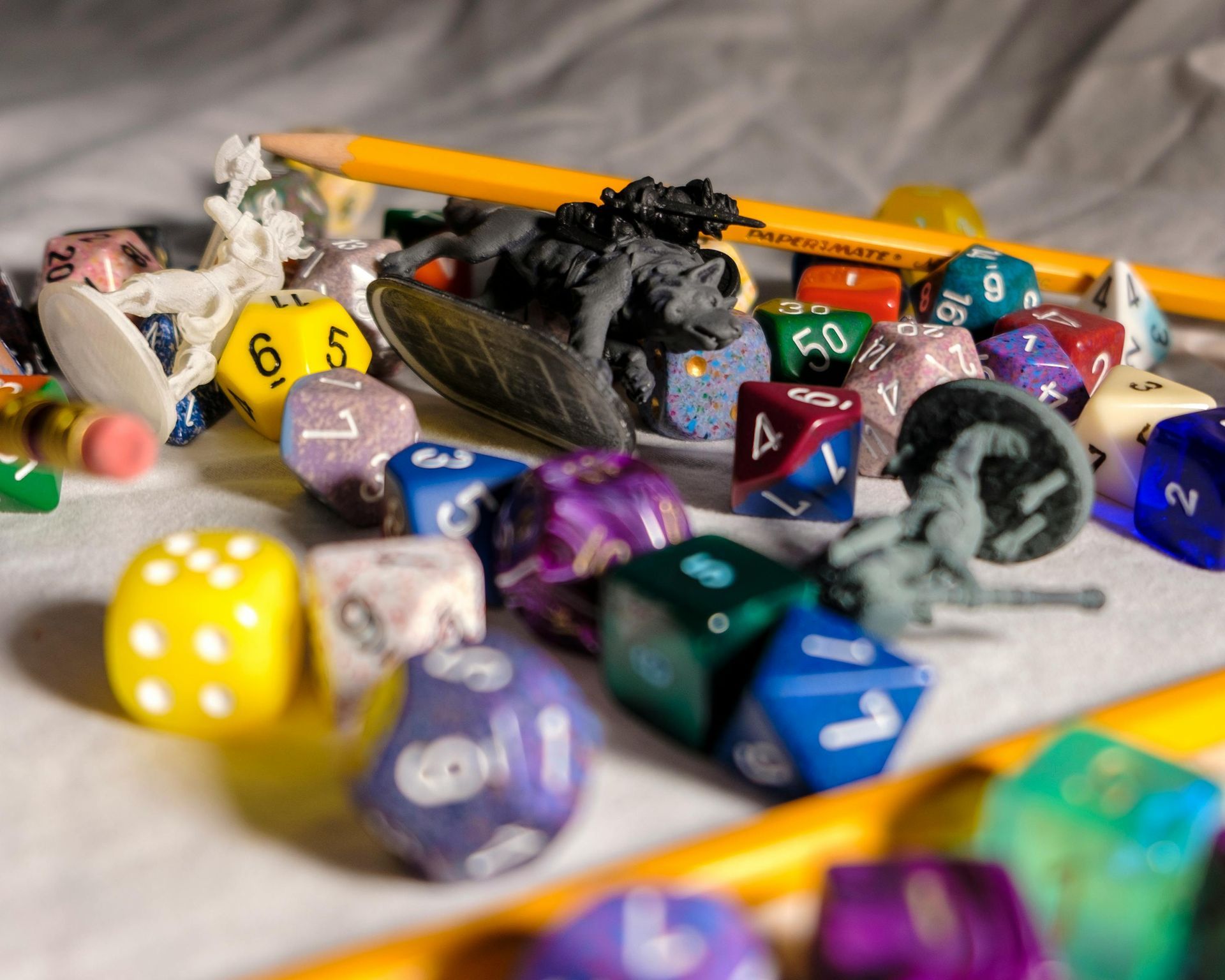 Scattered colorful polyhedral dice and pencils on a tabletop