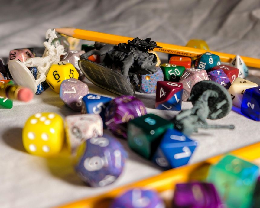Scattered colorful polyhedral dice and pencils on a tabletop