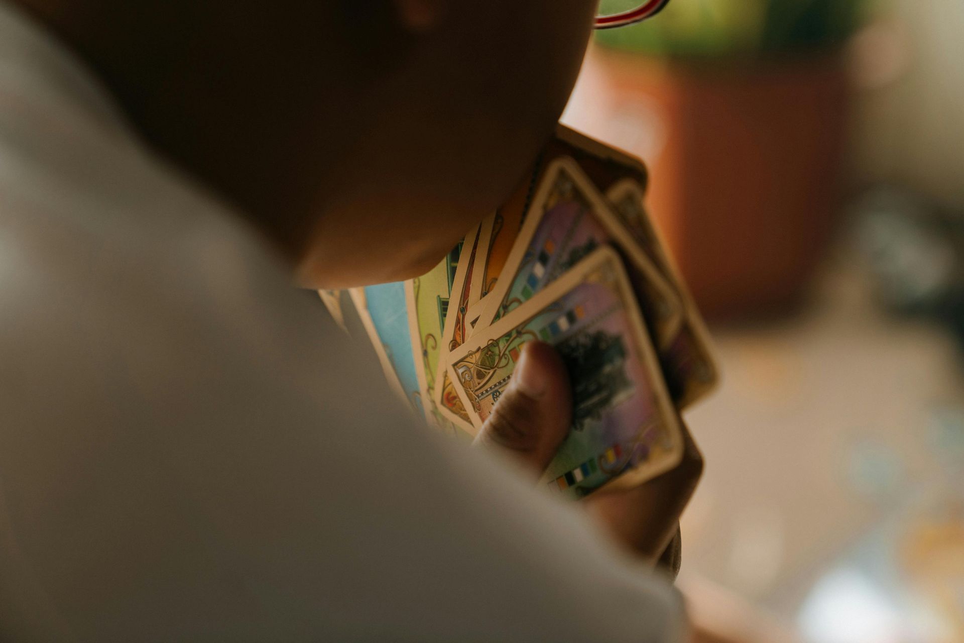 Person holding a fan of colorful tarot cards indoors