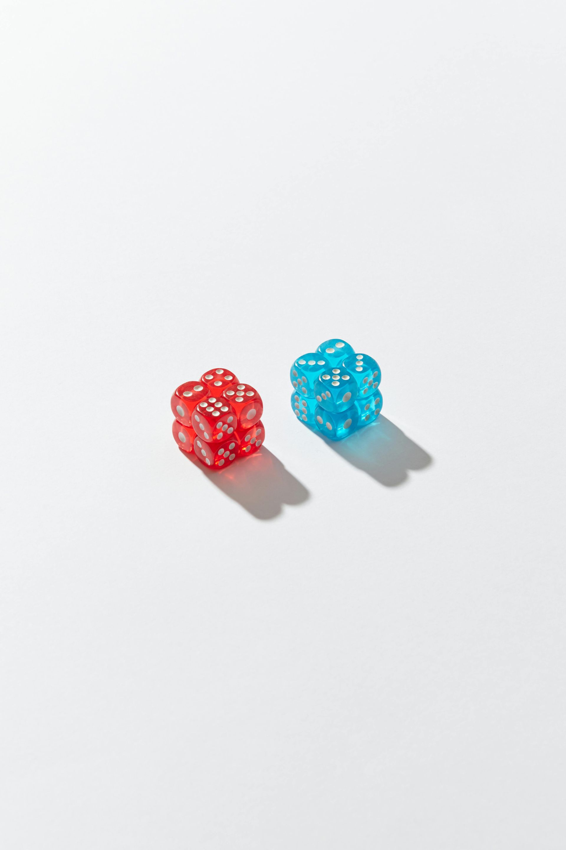 Two translucent dice, one red and one blue, on a white surface with shadows.
