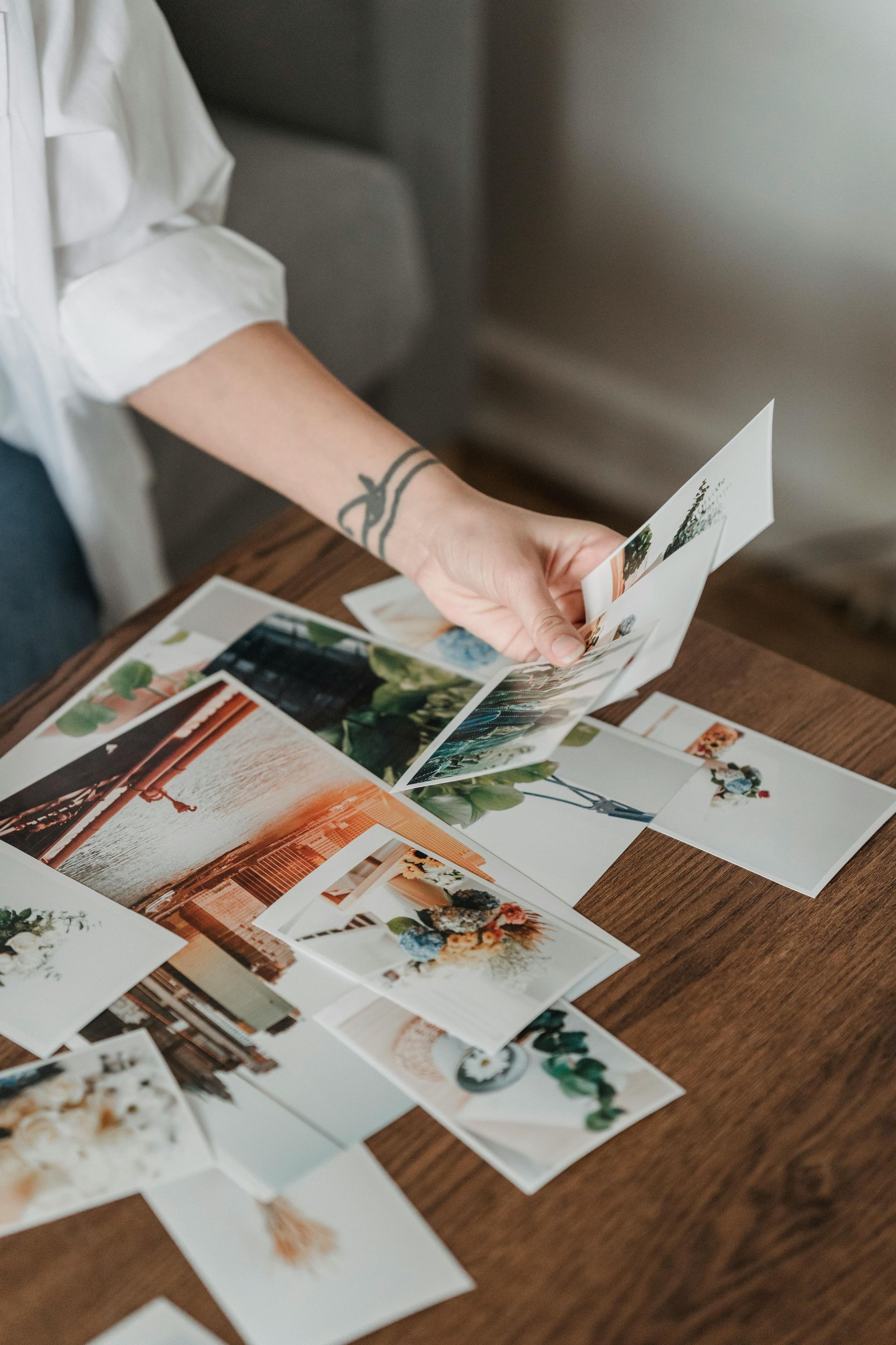 Person arranging printed photo cards on a wooden table