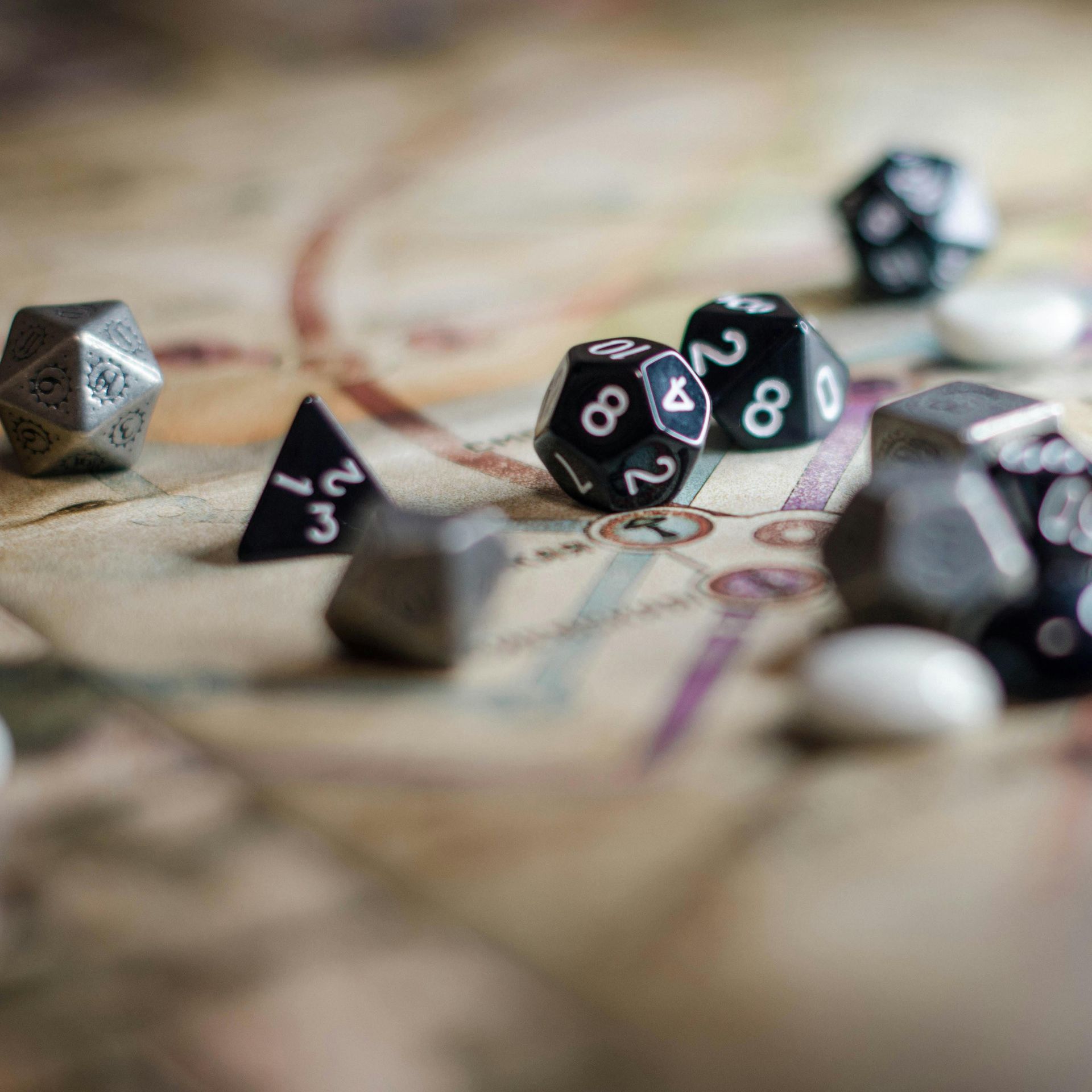 Black polyhedral dice scattered on a map, with a few in sharp focus on the table