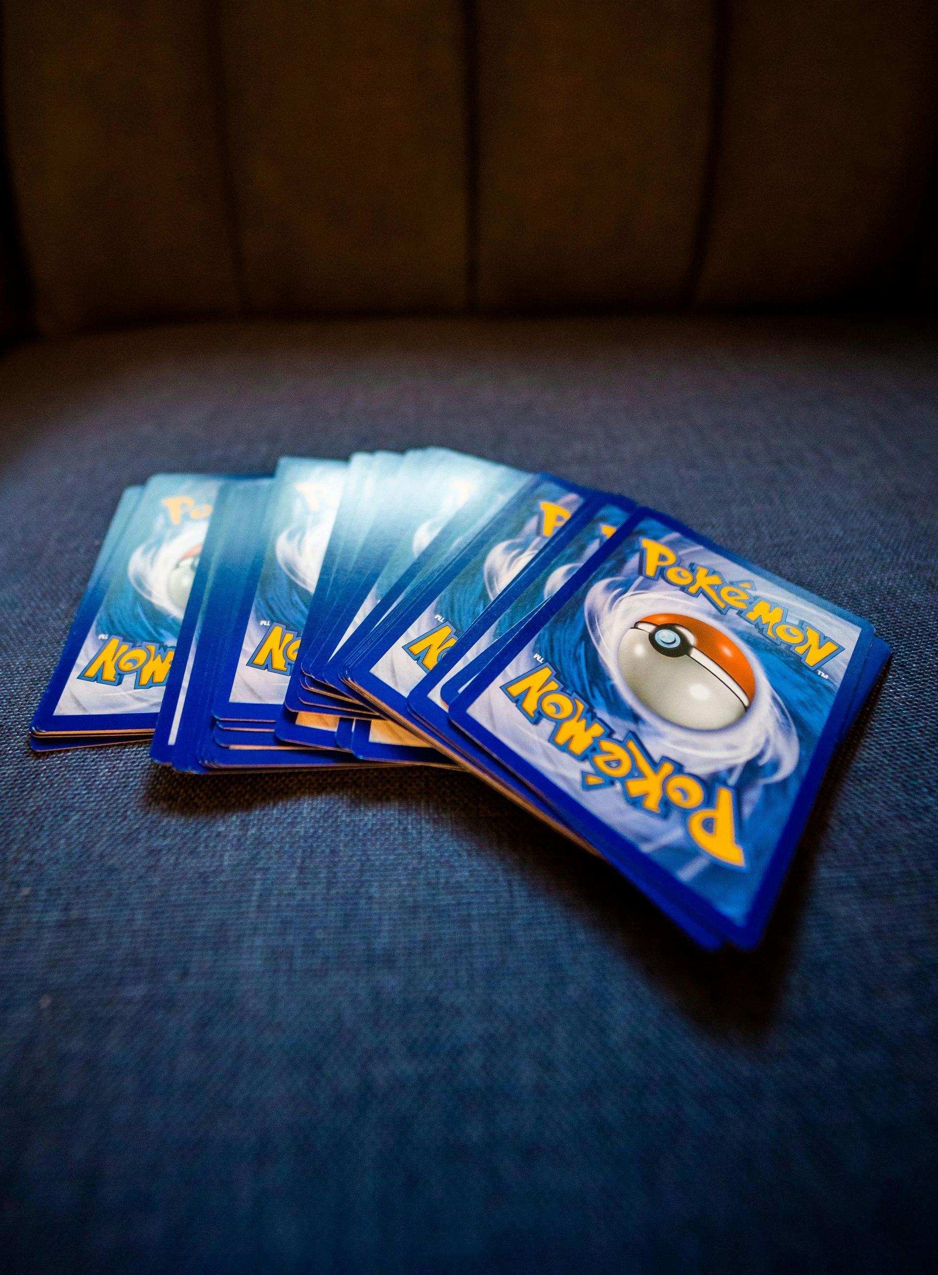 Stack of blue-backed Pokémon cards on a blue surface with a blurred wooden background