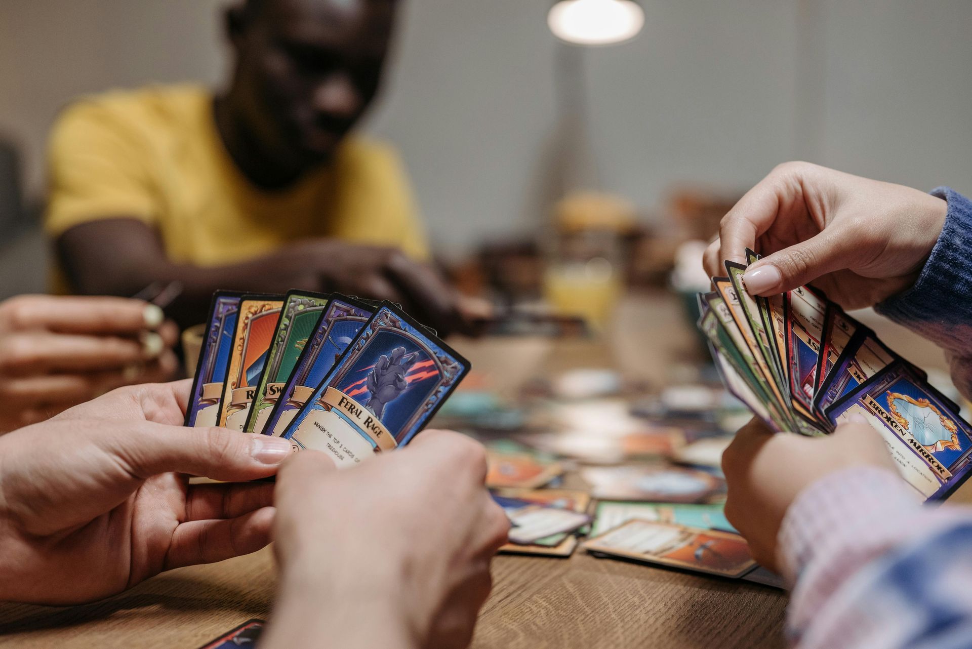 Hands holding colorful trading cards over a tabletop game in progress
