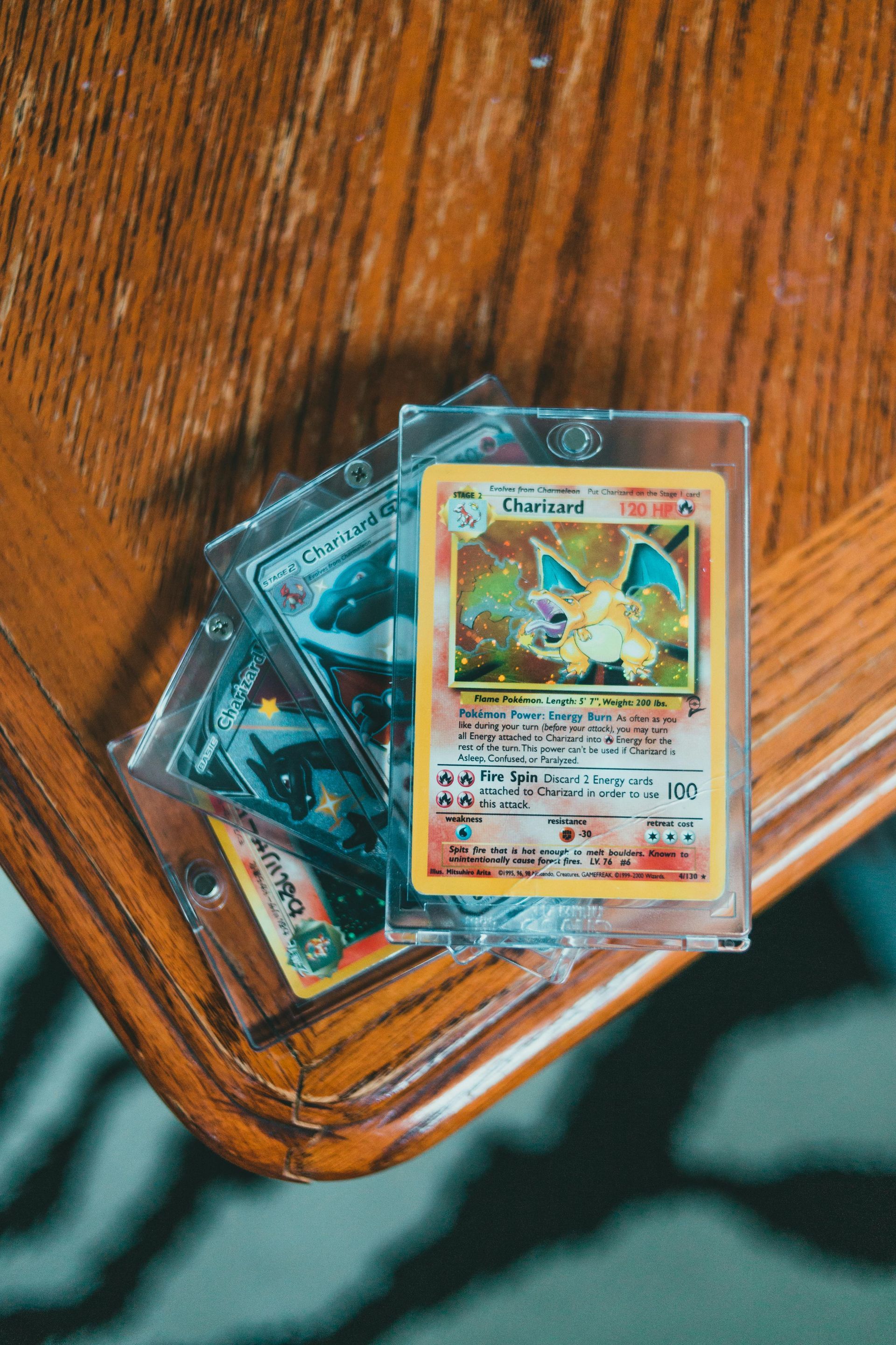 A stack of card game cards in clear sleeves on a wooden chair armrest.