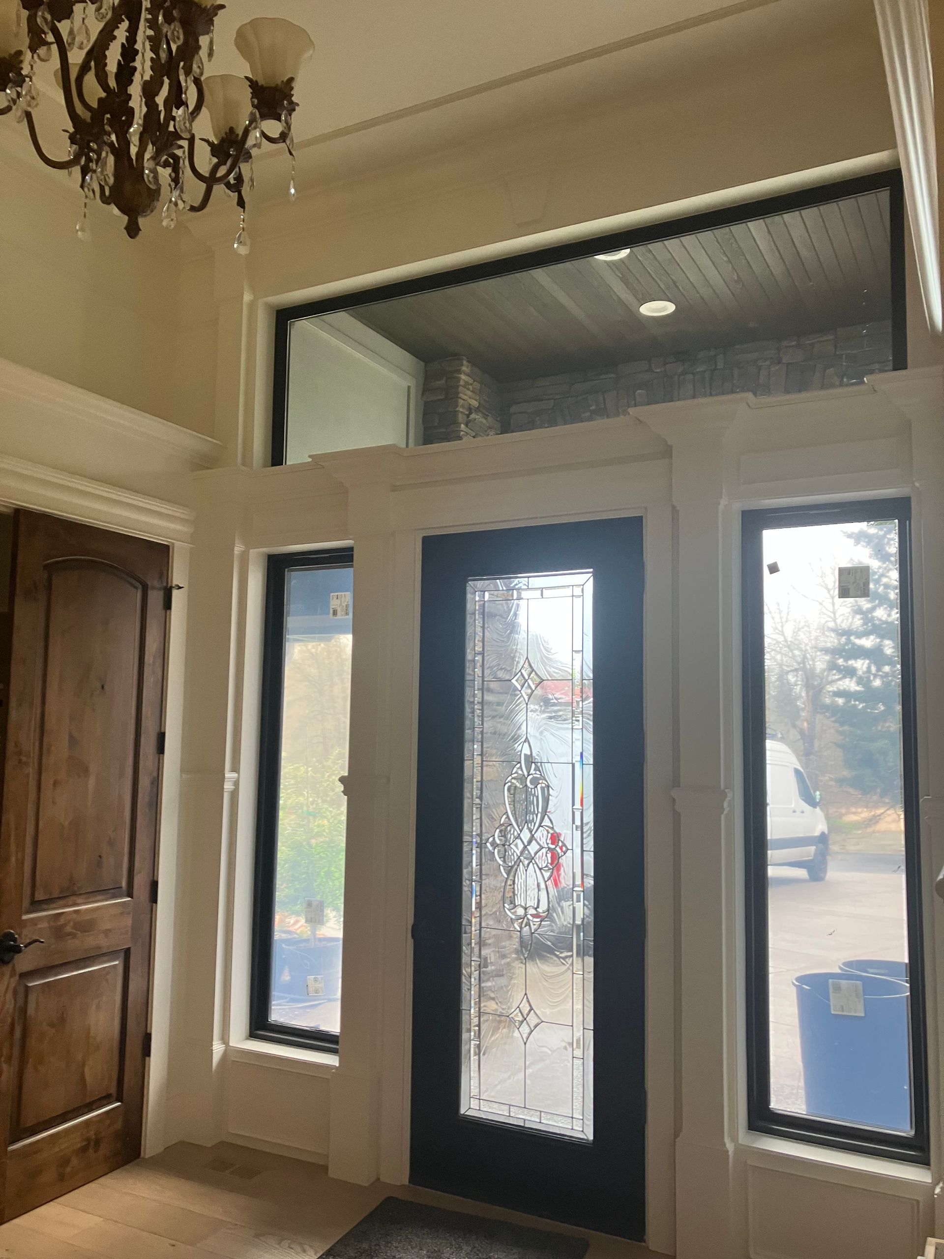 Front entryway with white door, sidelights, and a glass transom above, viewed from inside a foyer
