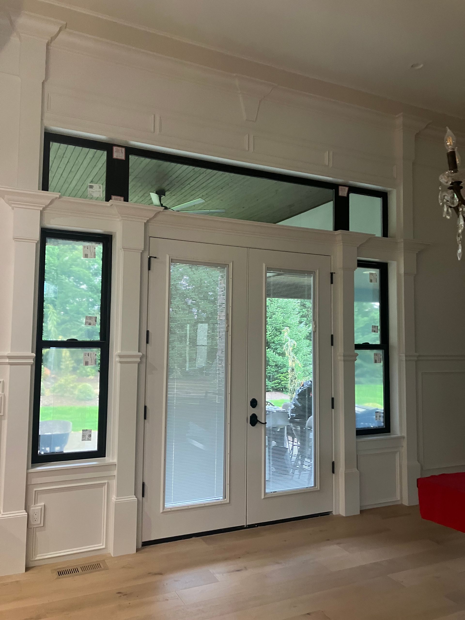 White French doors with sidelights in a bright room, showing greenery outside.