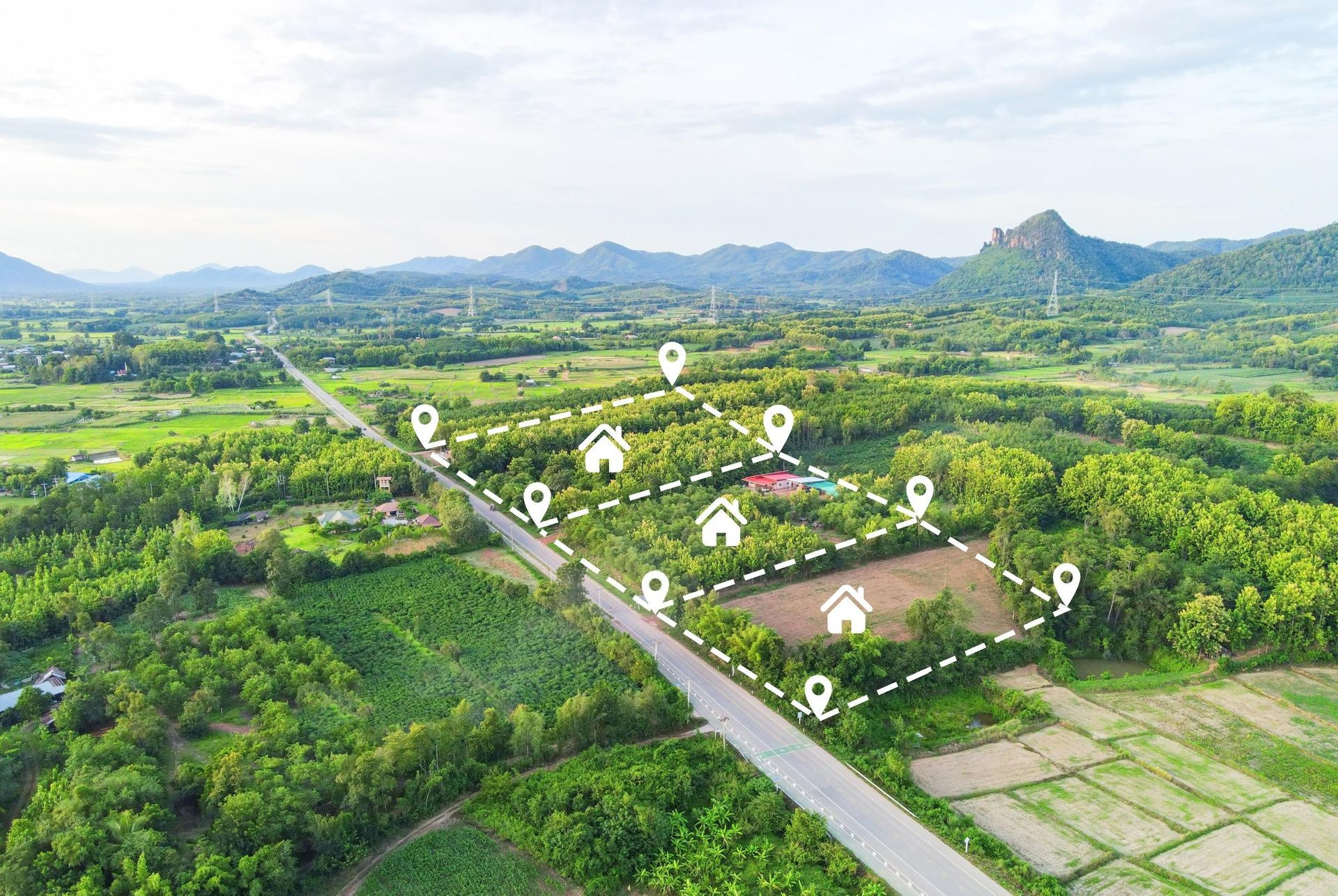 Aerial view of land plots marked with white outlines, pins, and house icons.