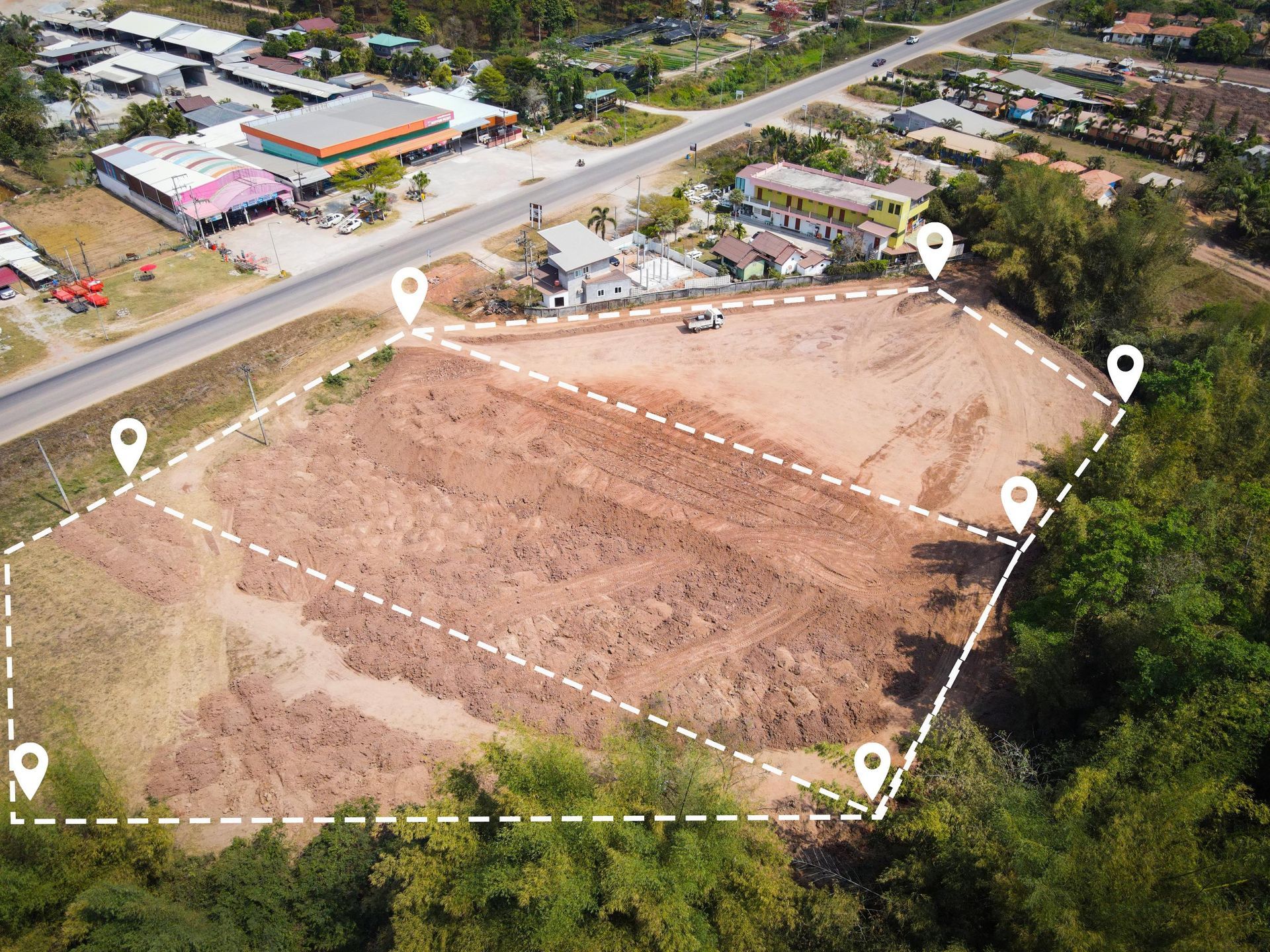Aerial view of a cleared plot of land marked with white boundary lines.