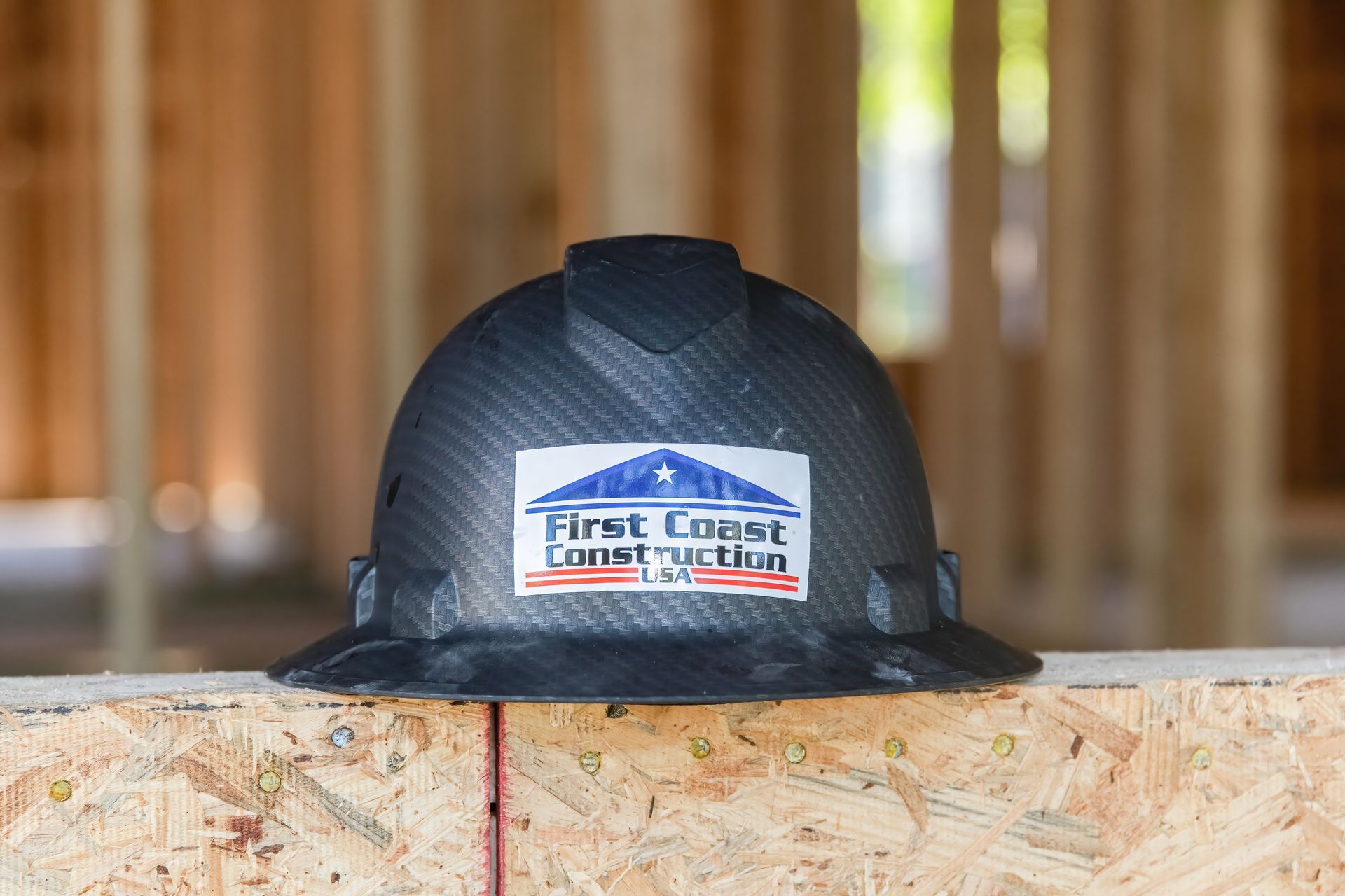 Black hard hat with a U.S. Forest Service sticker resting on a wooden beam outdoors