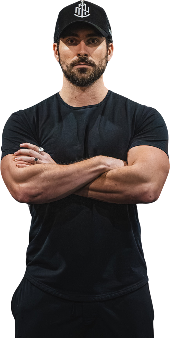 A man with a beard and a hat is standing with his arms crossed.