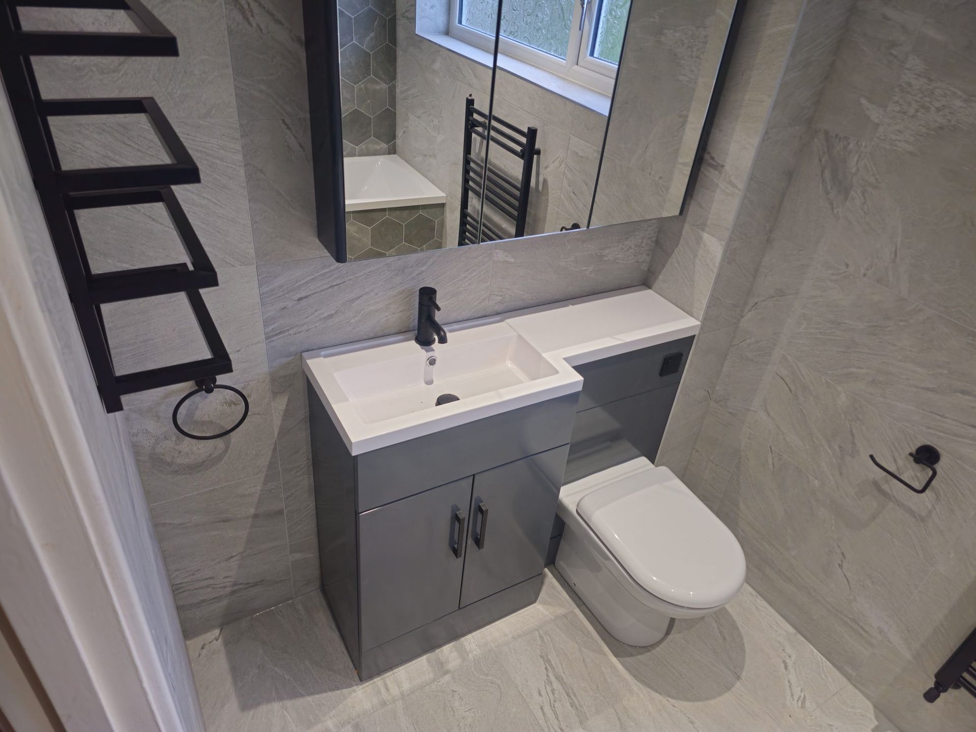 En-suite with grey vanity unit and black towel rail