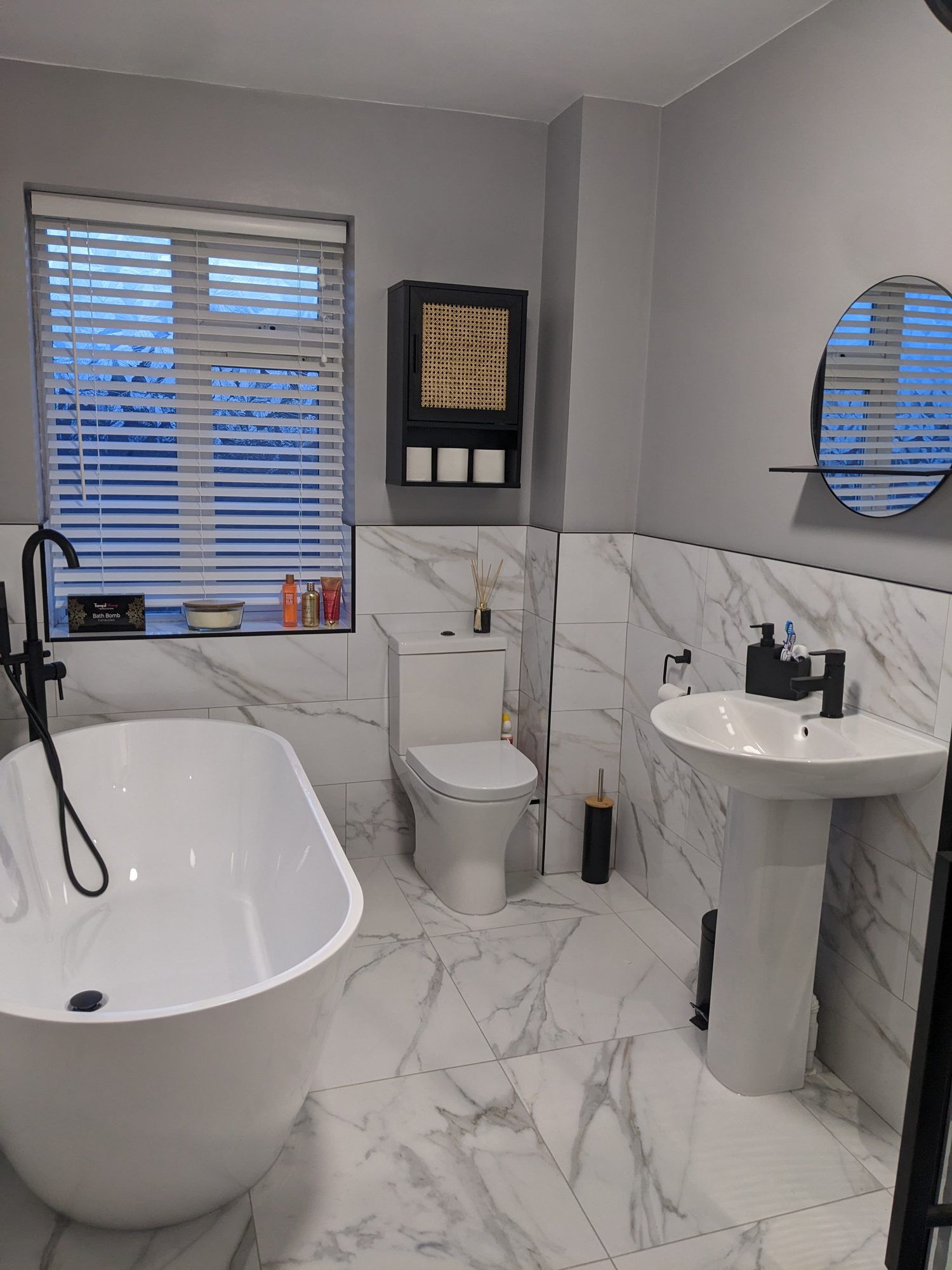 Freestanding bath with marble-effect tiles and black fittings, installed by Mark at MHC Bathroom Installations