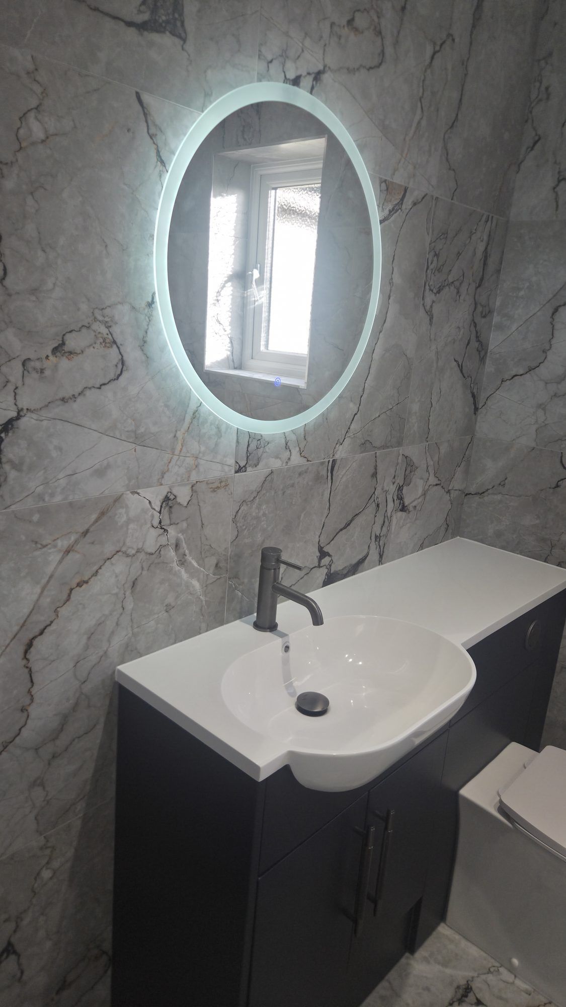 Marble-effect wall panels with an LED mirror and dark vanity unit