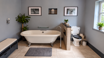 Roll-top bath beside a half-height partition wall in a full bathroom installation