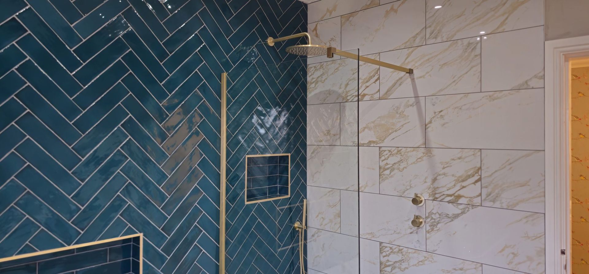 Walk-in shower with teal herringbone tiles and brushed gold fittings