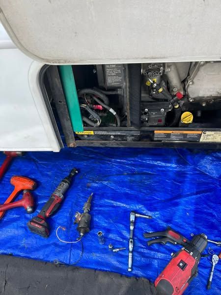 Open electrical compartment with blue tarp and assorted tools laid out on the floor