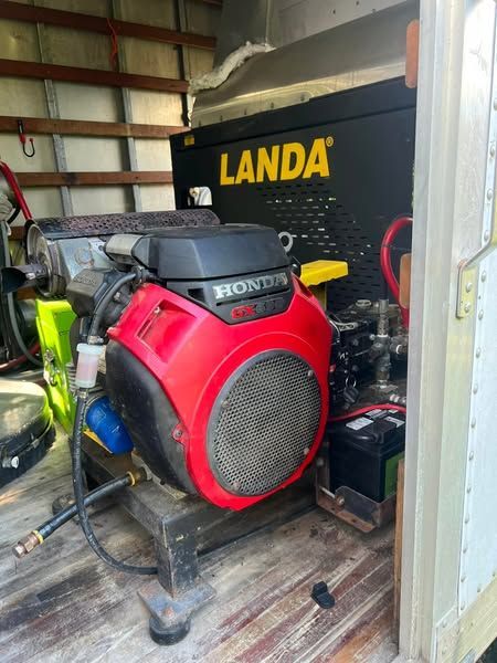 Red Honda generator beside a black Landa pressure washer in a utility shed
