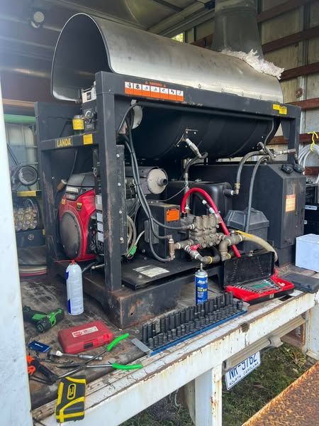 Open generator with exposed engine components on a workbench in a garage or workshop, tools scattered around