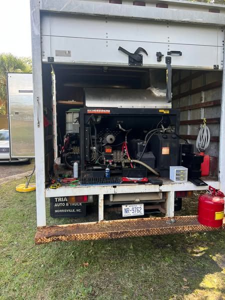 Open truck trailer with tools and equipment inside, parked on grass with a red fuel can in front.
