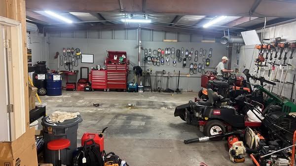 Garage interior with lawn equipment, tools, and a red toolbox along the back wall
