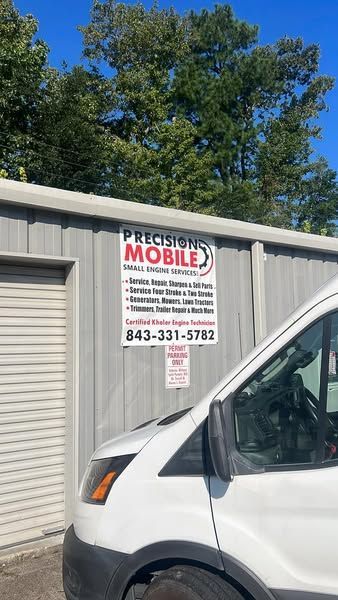 White van parked by a storage building with a “MOBILE” sign and blue sky above