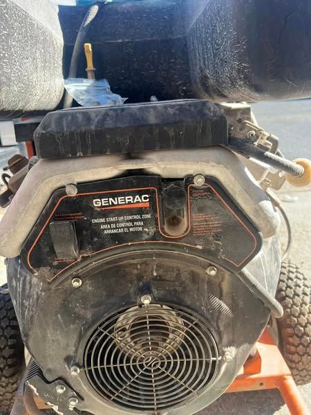Close-up of a Generac generator with a black fan cover and orange frame outdoors