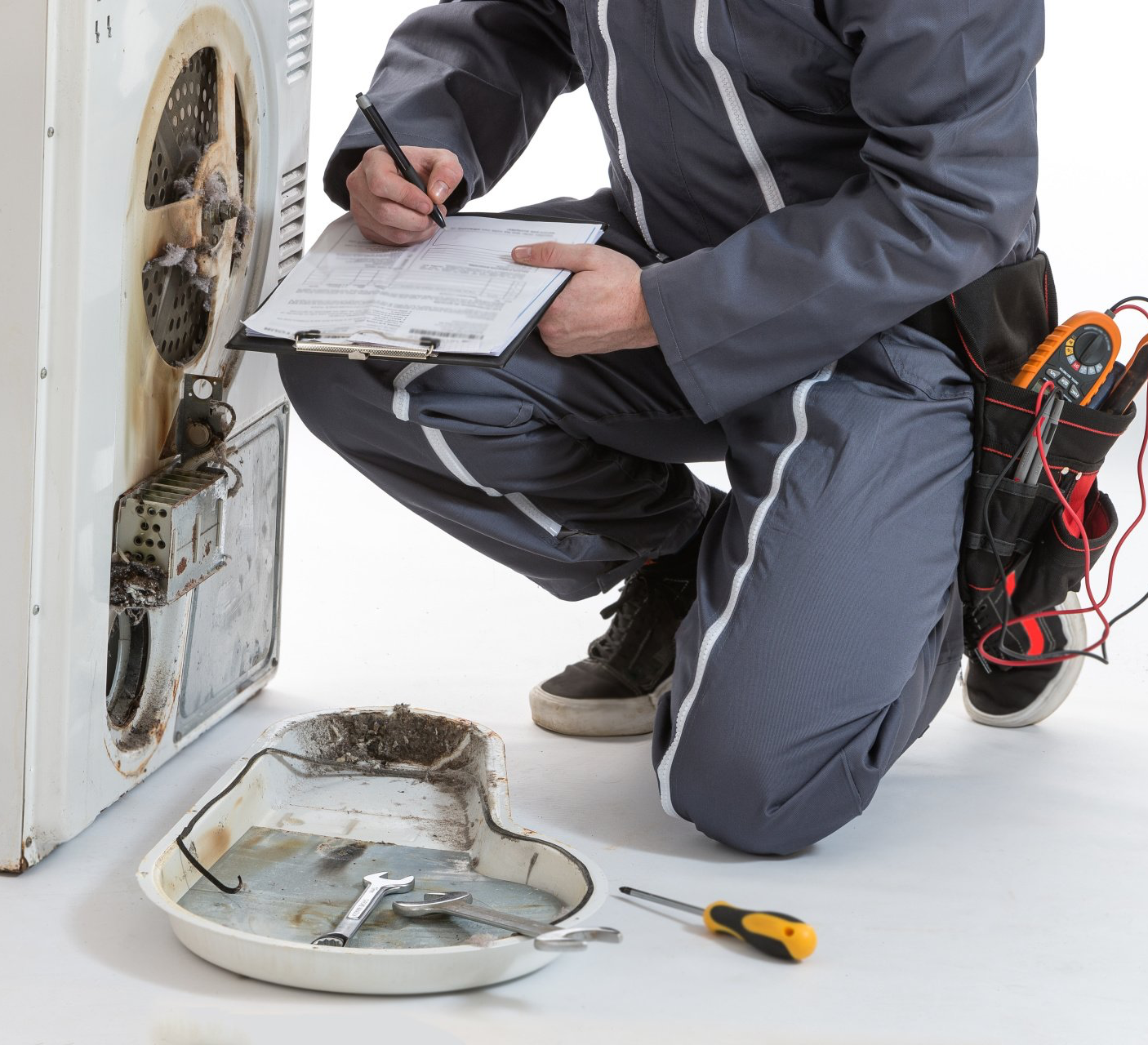 A man is kneeling down next to a washing machine and writing on a clipboard