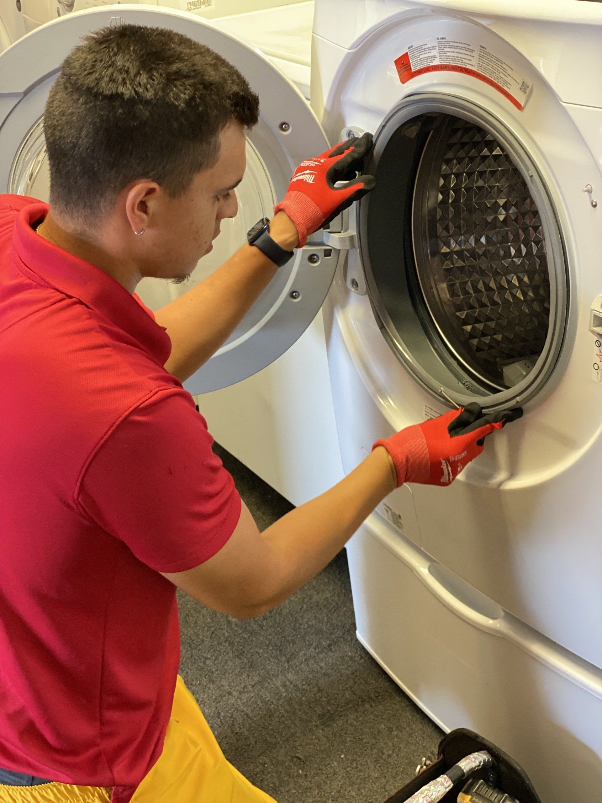 A man in a red shirt is working on a washing machine