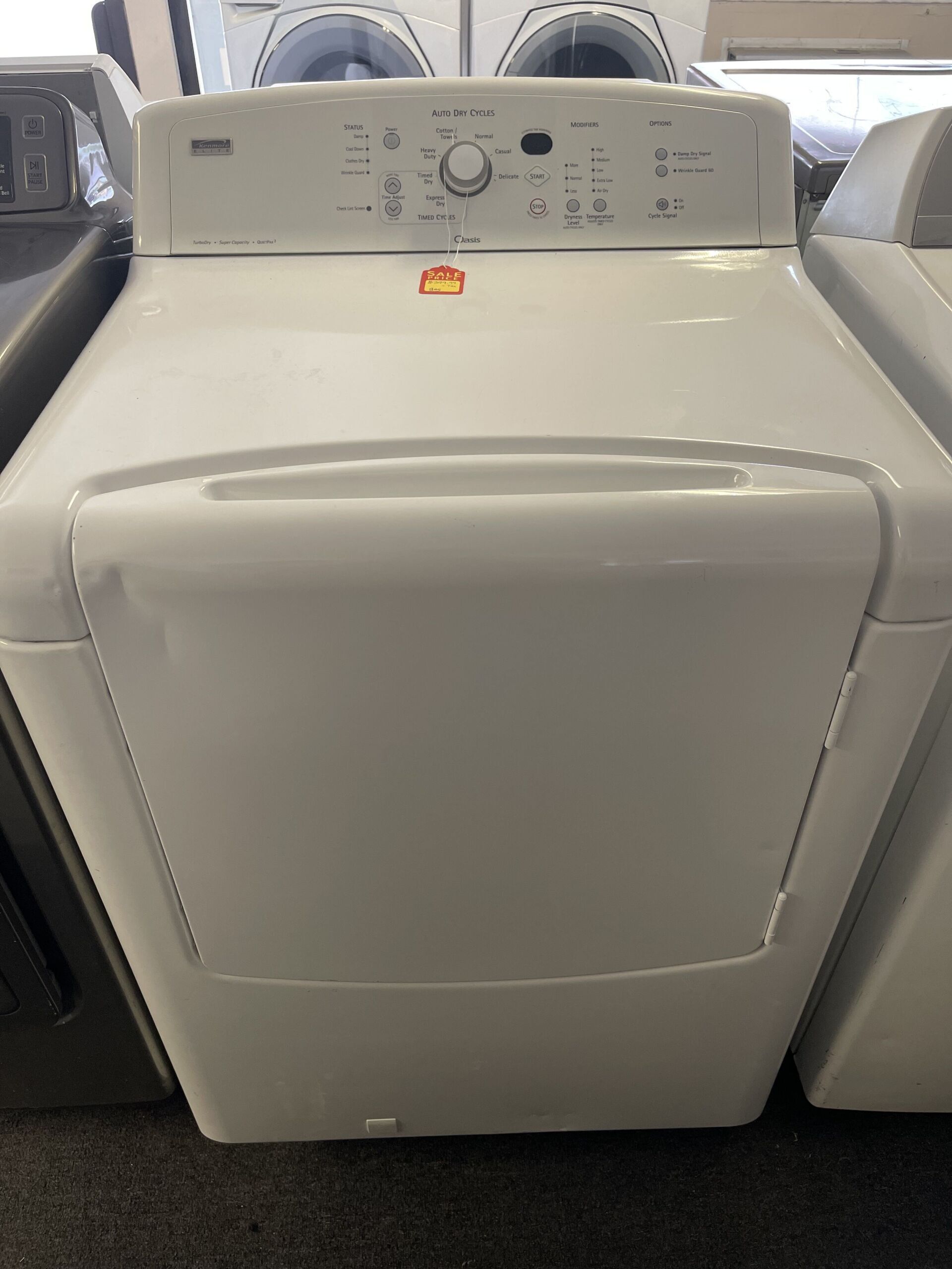 A white dryer is sitting on top of a carpet in a store.