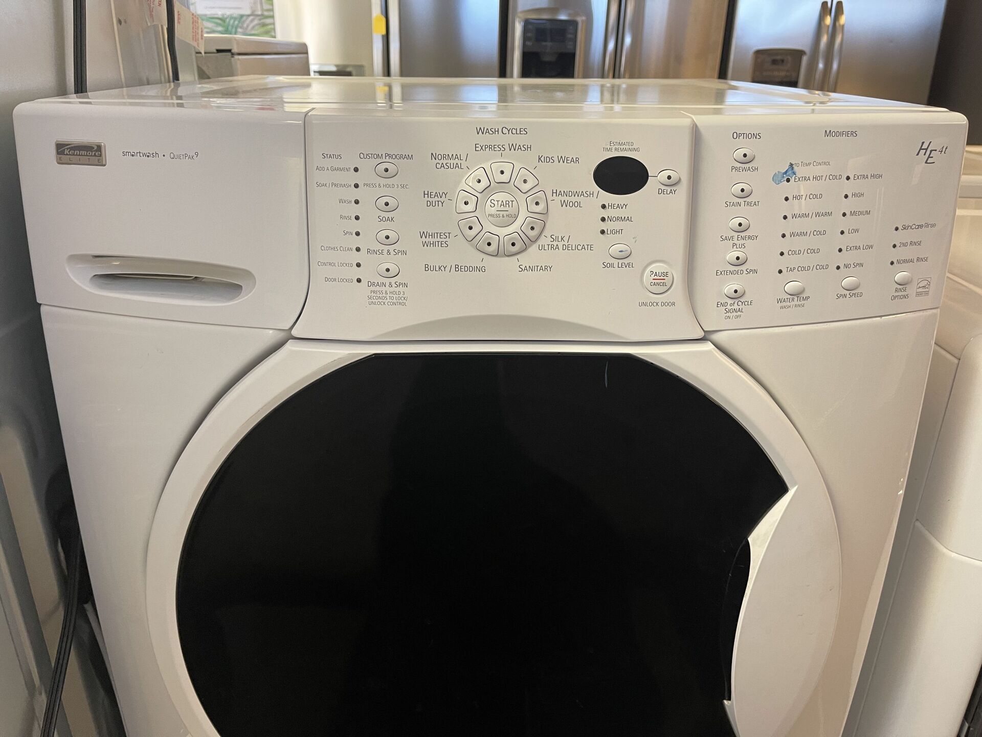 A white washing machine with a black door is sitting on a counter.