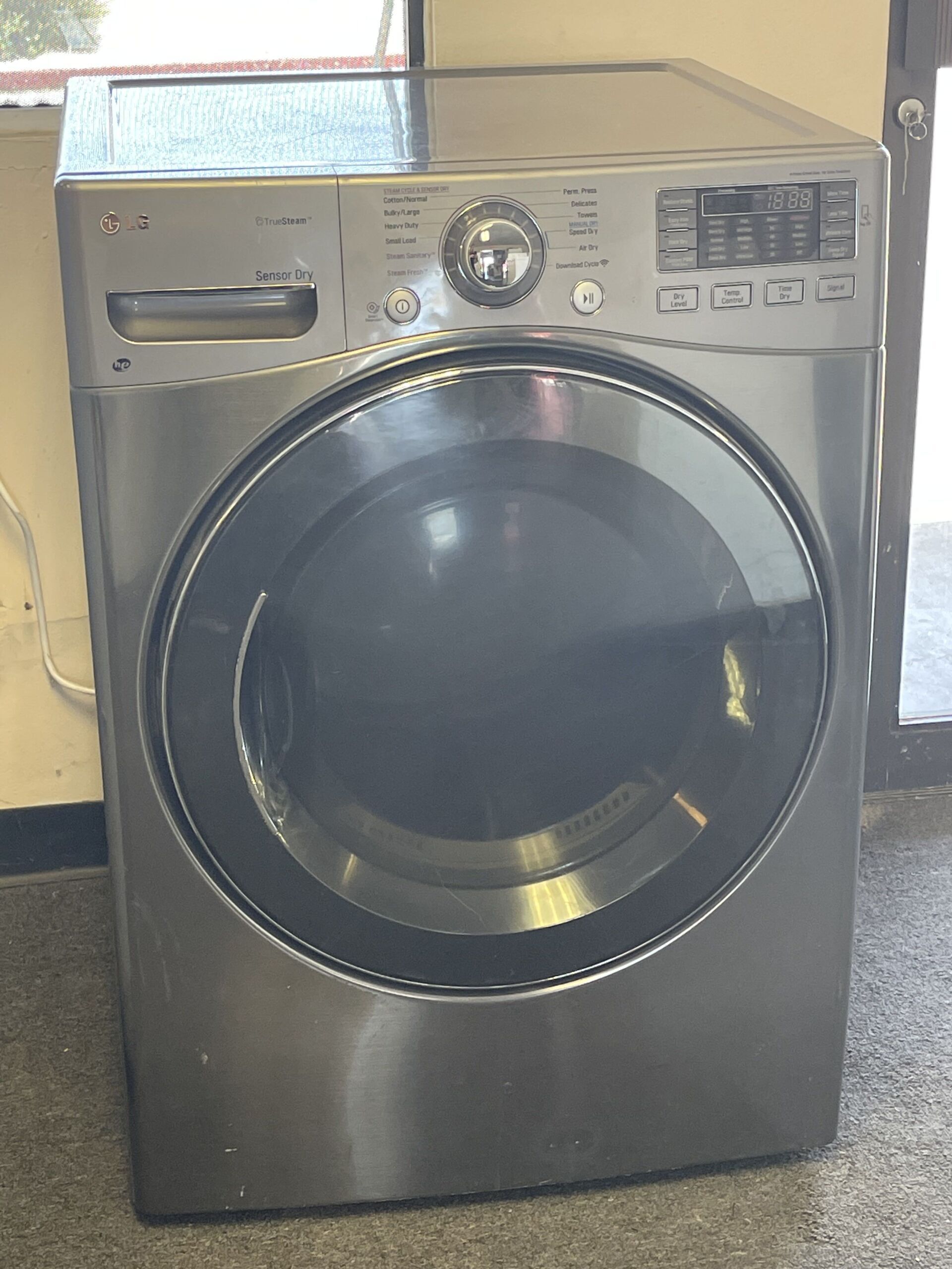 A stainless steel washing machine and dryer are sitting in a room.