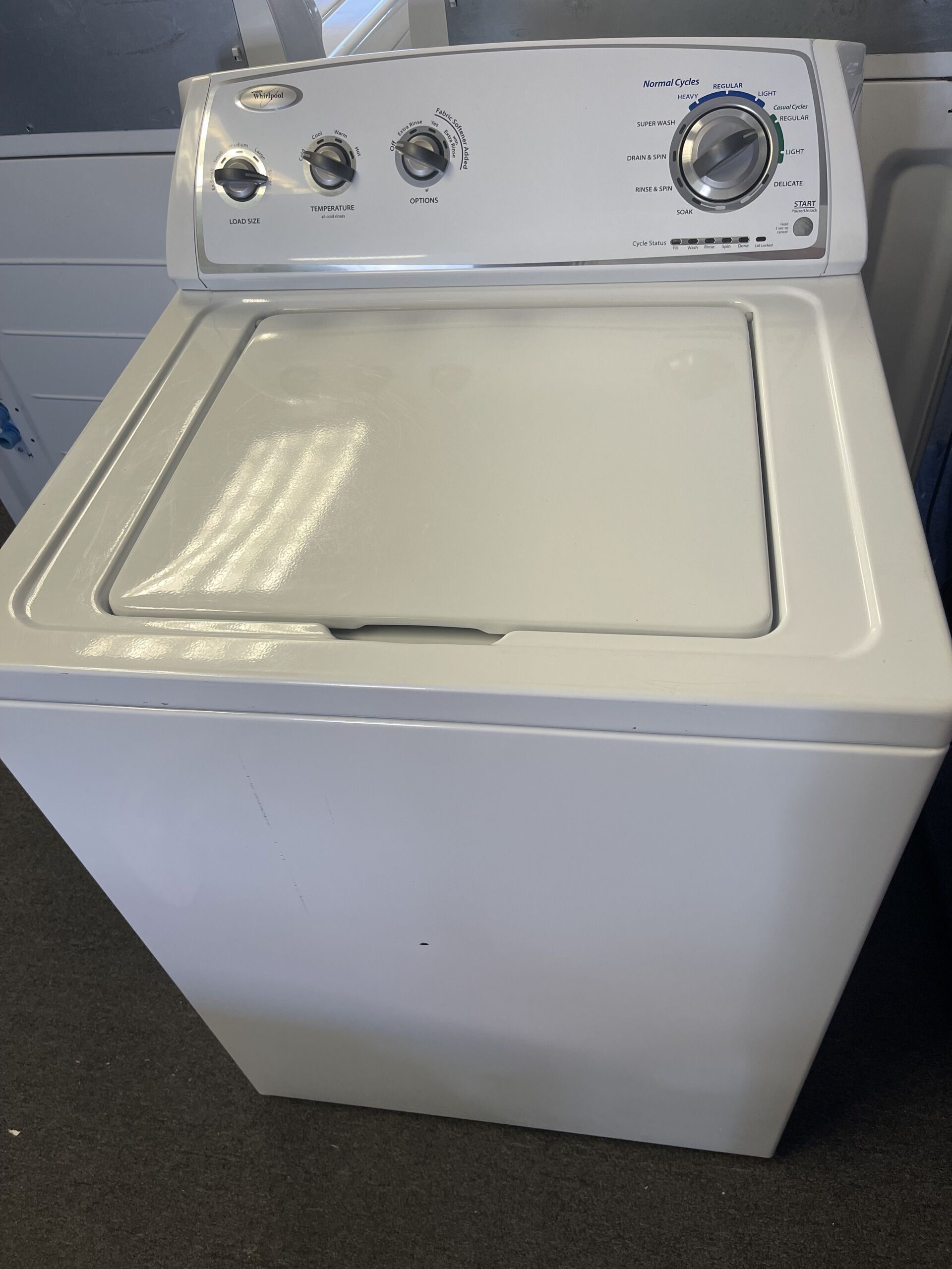 A white washing machine is sitting on a carpeted floor.