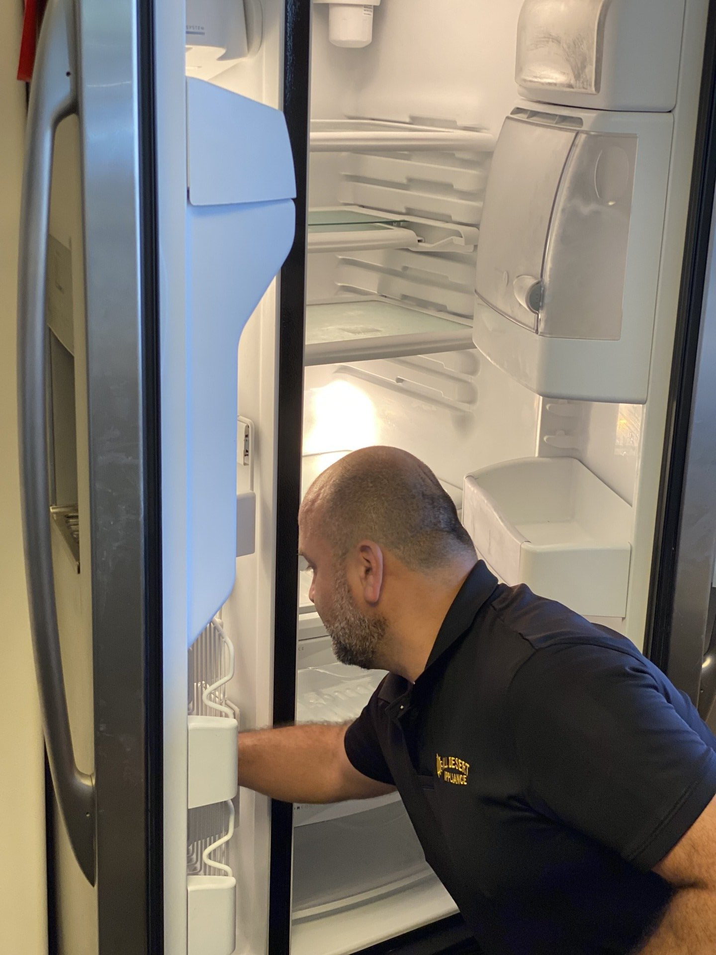 A man in a black shirt is opening the door of a refrigerator.