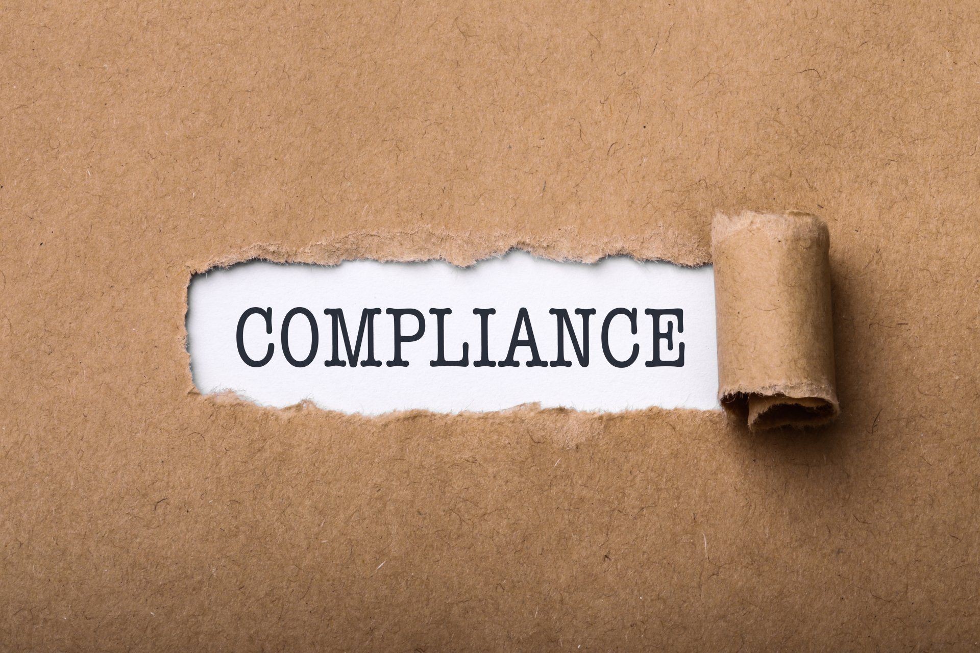 Close-up shot of paper tear with text Compliance.