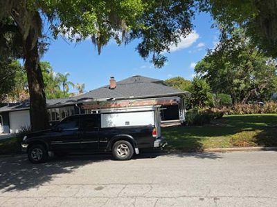 Black work van parked on a suburban street in front of a house with trees and a lawn