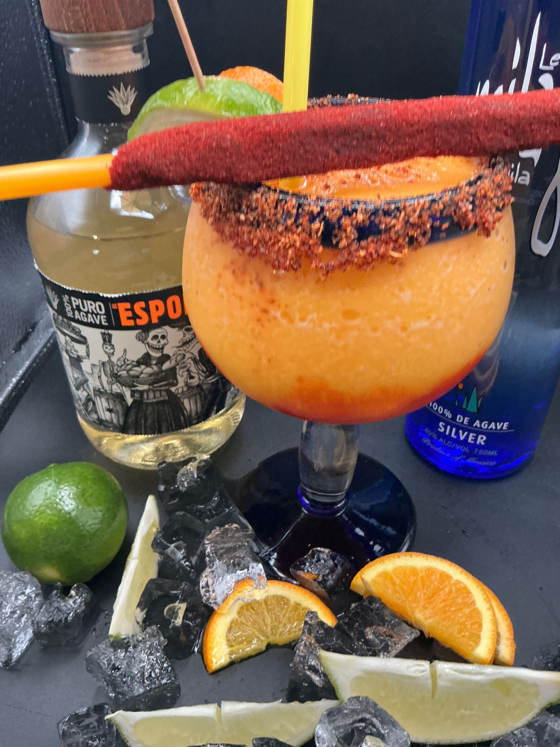 Mango margarita in a rimmed glass with tequila and fruit garnishes.
