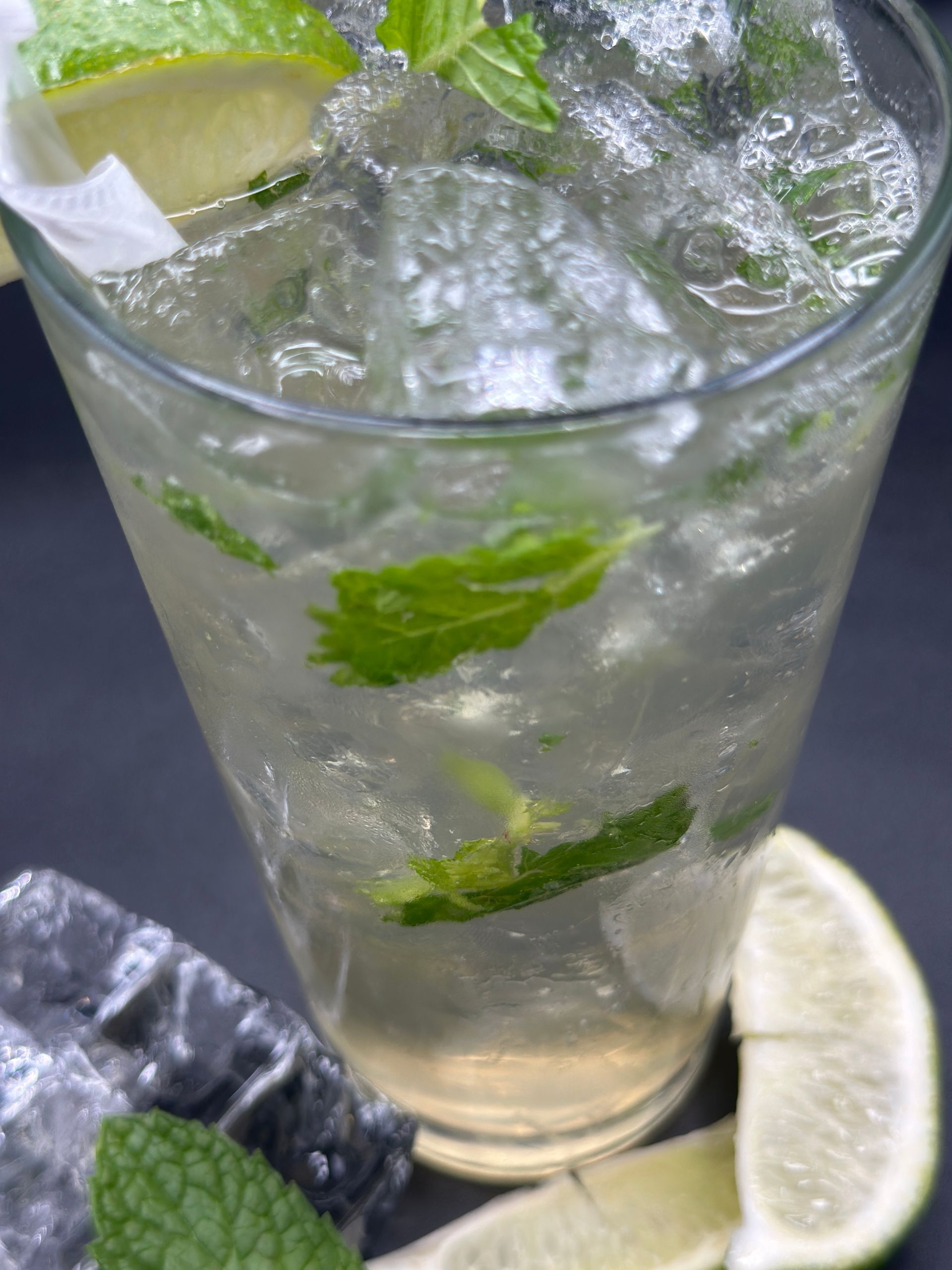 Mojito cocktail in a glass with ice, mint, and lime garnish.