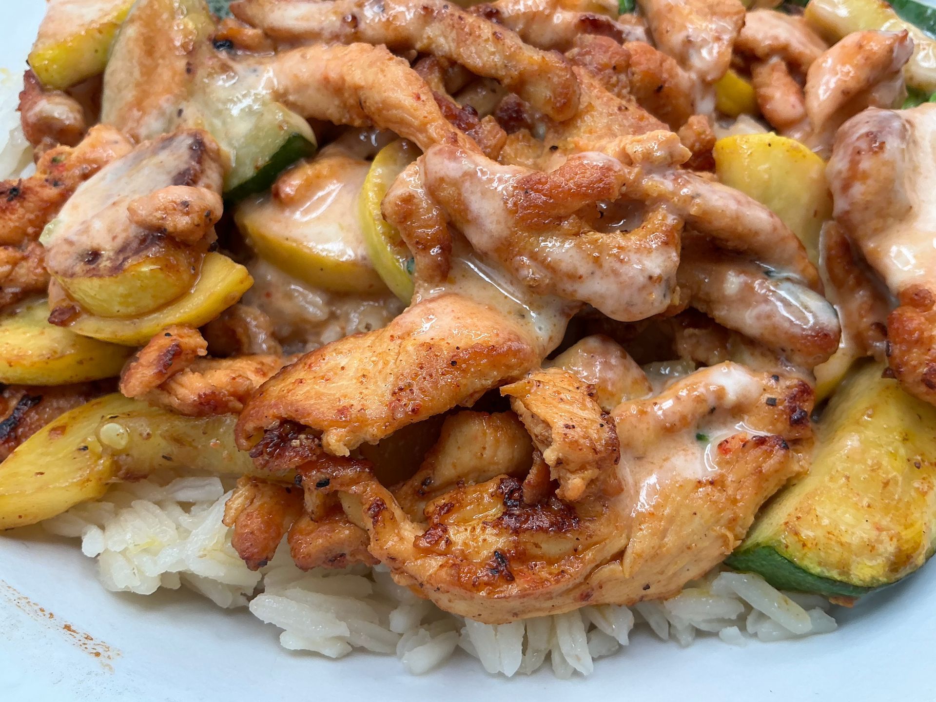 Chicken and zucchini stir-fry with creamy sauce served over white rice.