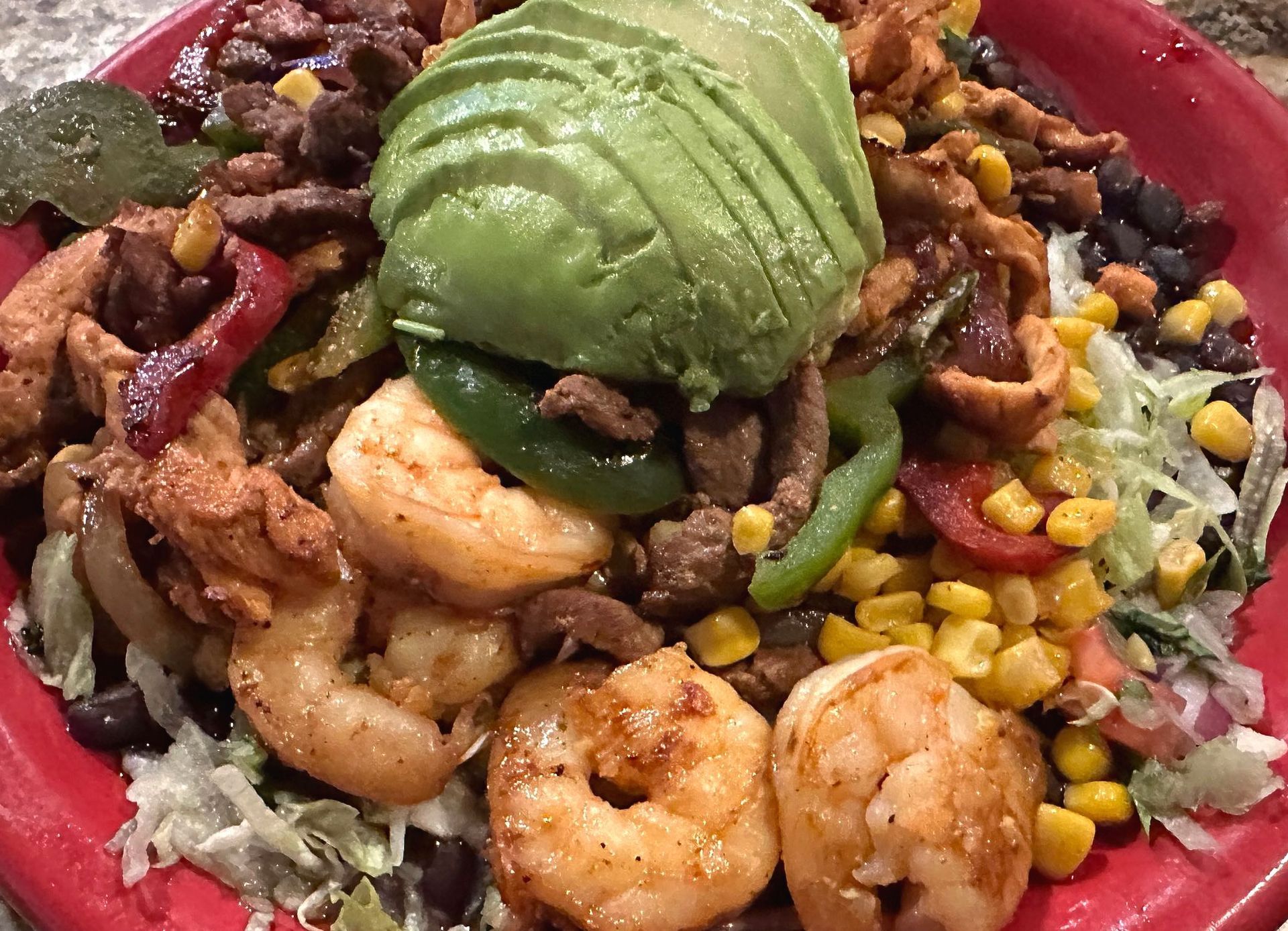 Grilled shrimp and chicken bowl with avocado, corn, and black beans.