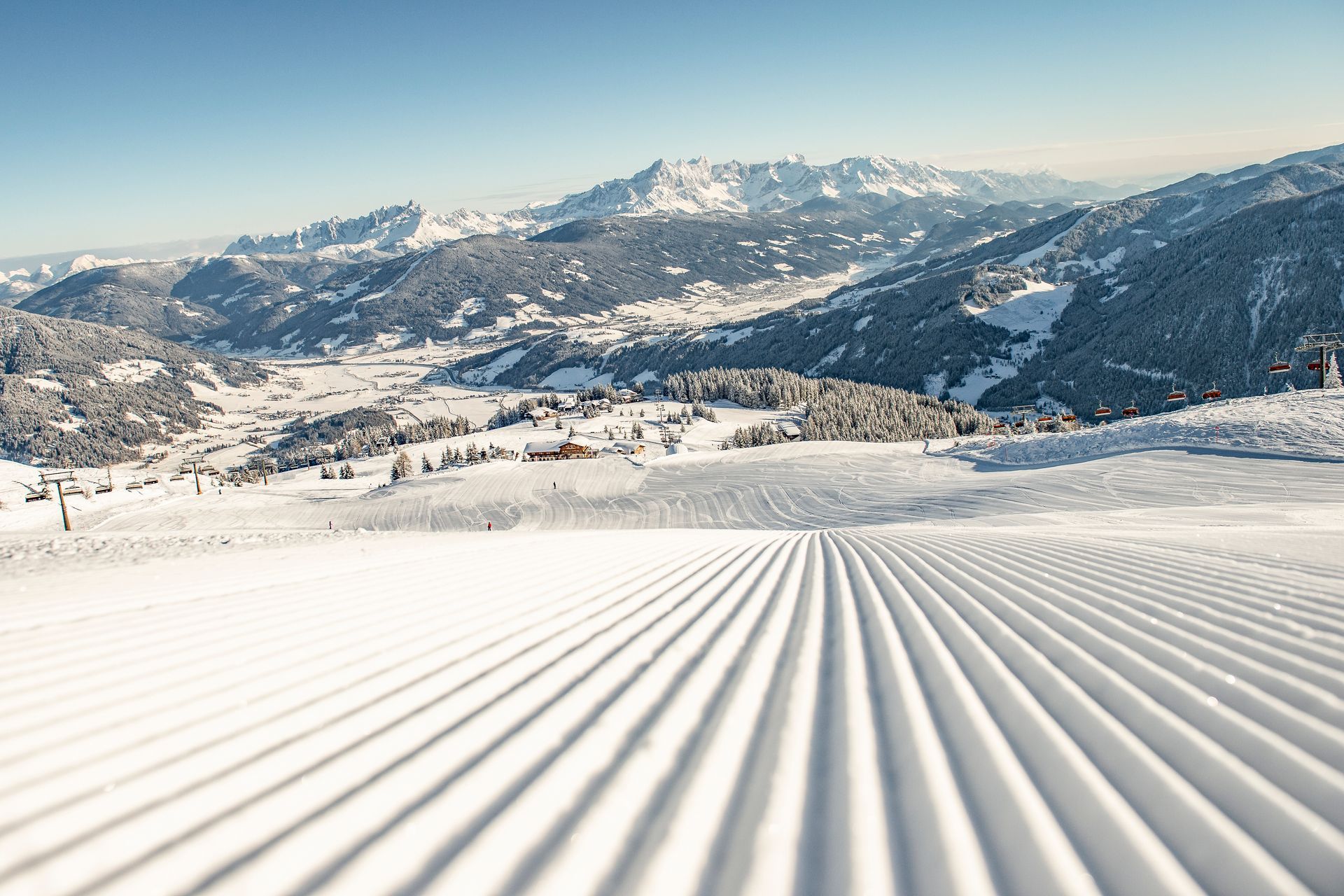 Präparierte Skipiste mit Bergblick unter klarem, blauem Himmel