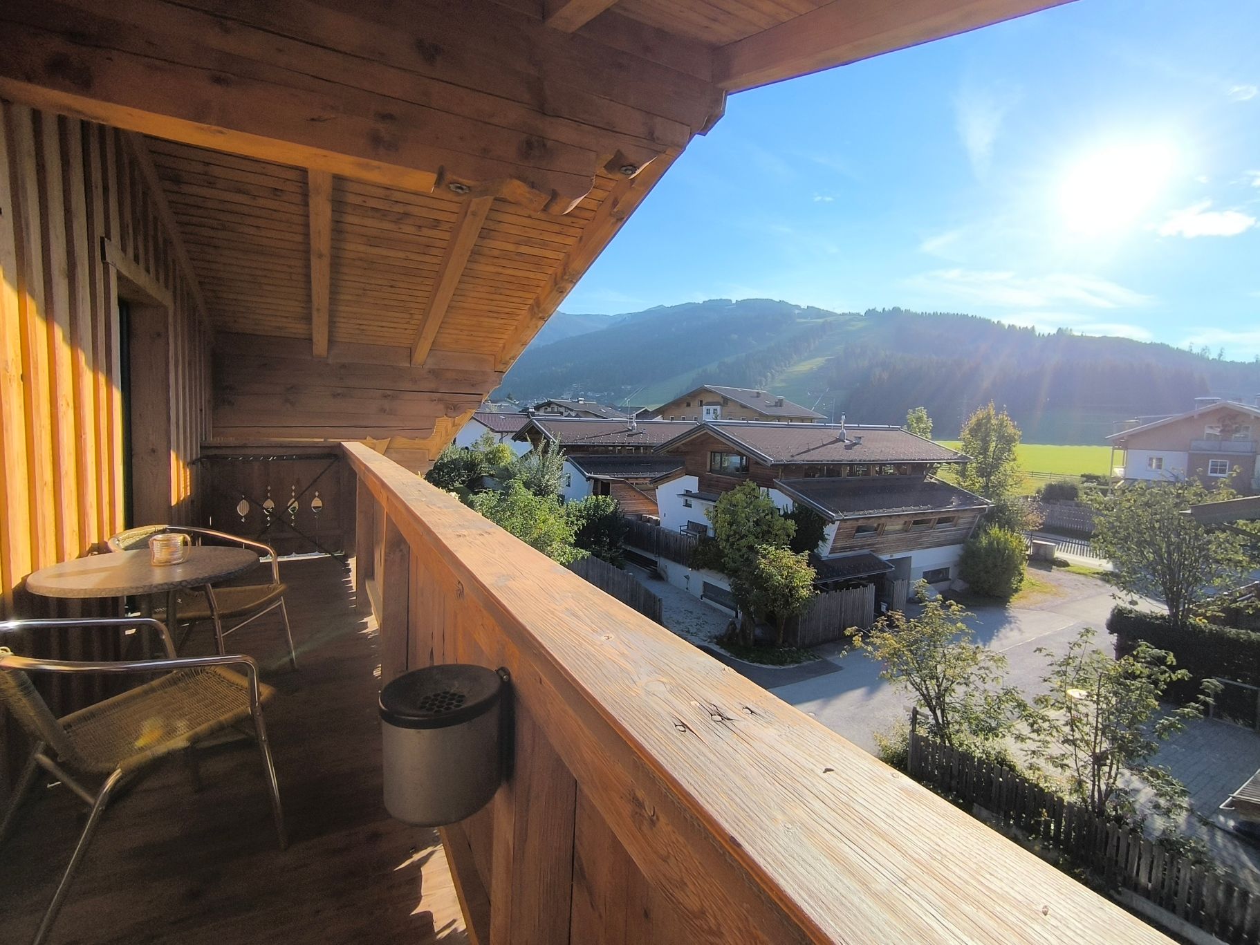 Holzbalkon mit Blick auf eine Bergstadt unter strahlend blauem Himmel