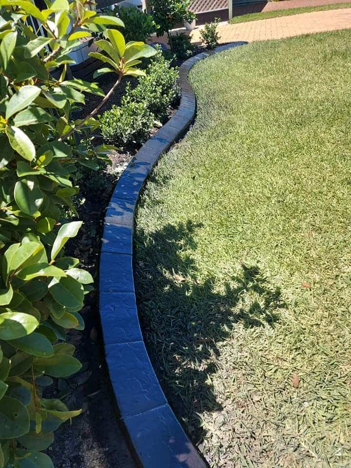 Dark Stone Edging Separates Lush Green Grass — Brett's Continuous Garden Edges In Lakewood, NSW
