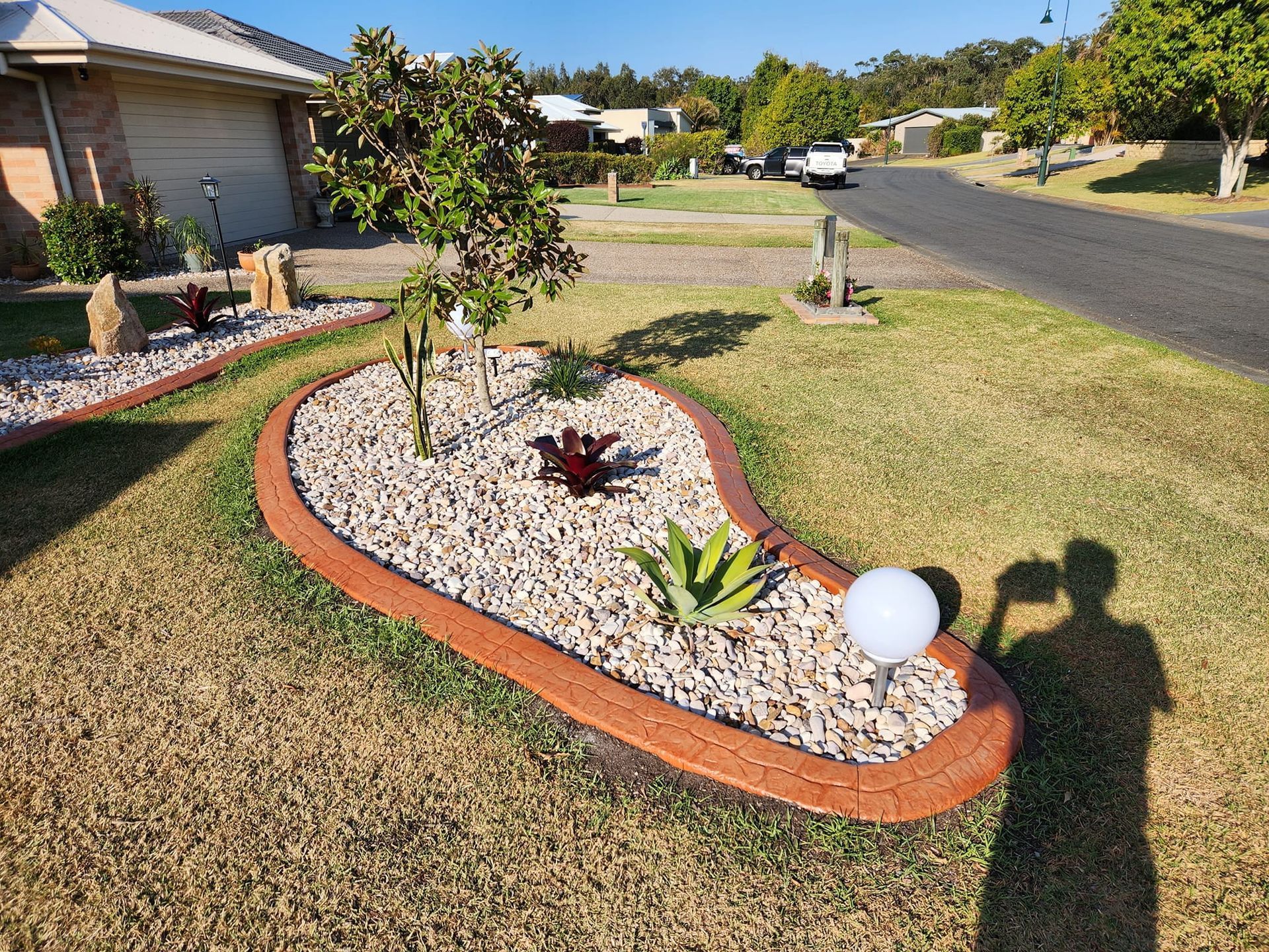 A Garden With Rocks and Plants in Front of a House — Brett's Continuous Garden Edges In Laurieton, NSW