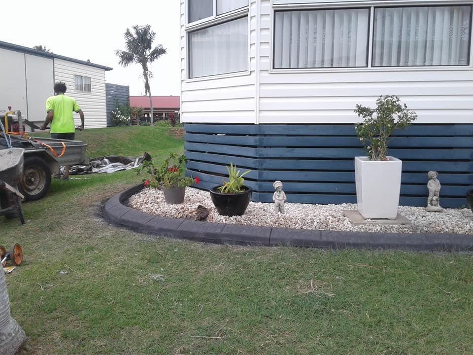A Landscaped Garden With Potted Plants and Small Statues — Brett's Continuous Garden Edges In Lake Cathie, NSW
