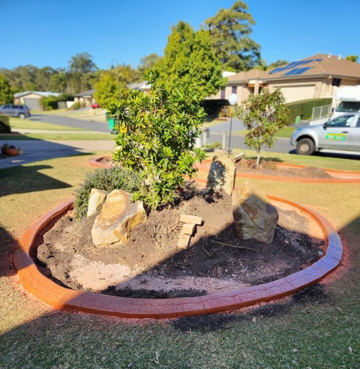 Circular Garden Bed With a Small Bush and Large Rocks — Brett's Continuous Garden Edges In Laurieton, NSW