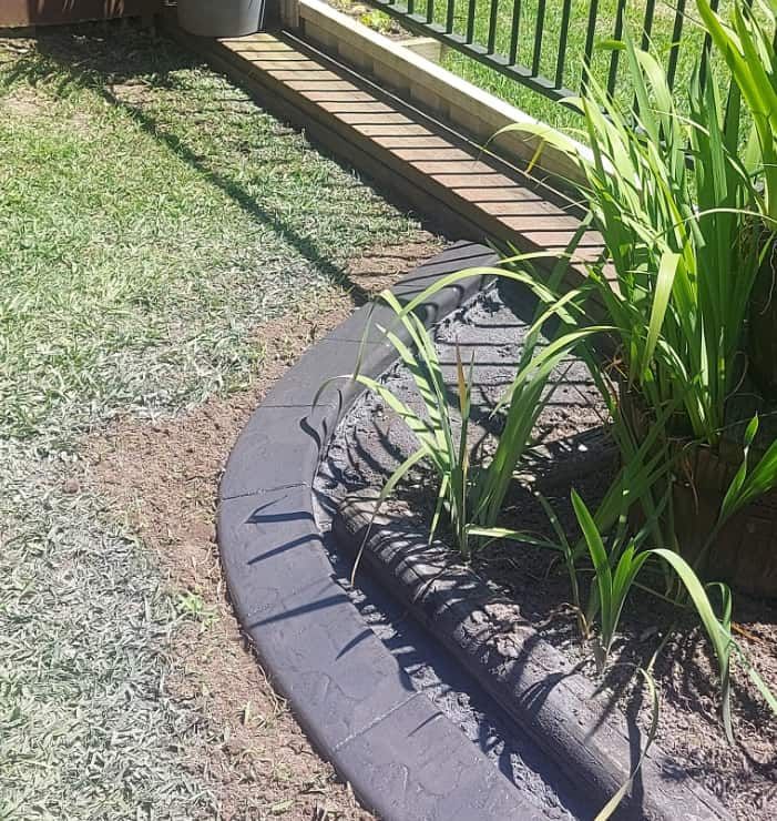 Curved Garden Bed Bordered by Black Stone Pavers — Brett's Continuous Garden Edges In Wauchope, NSW