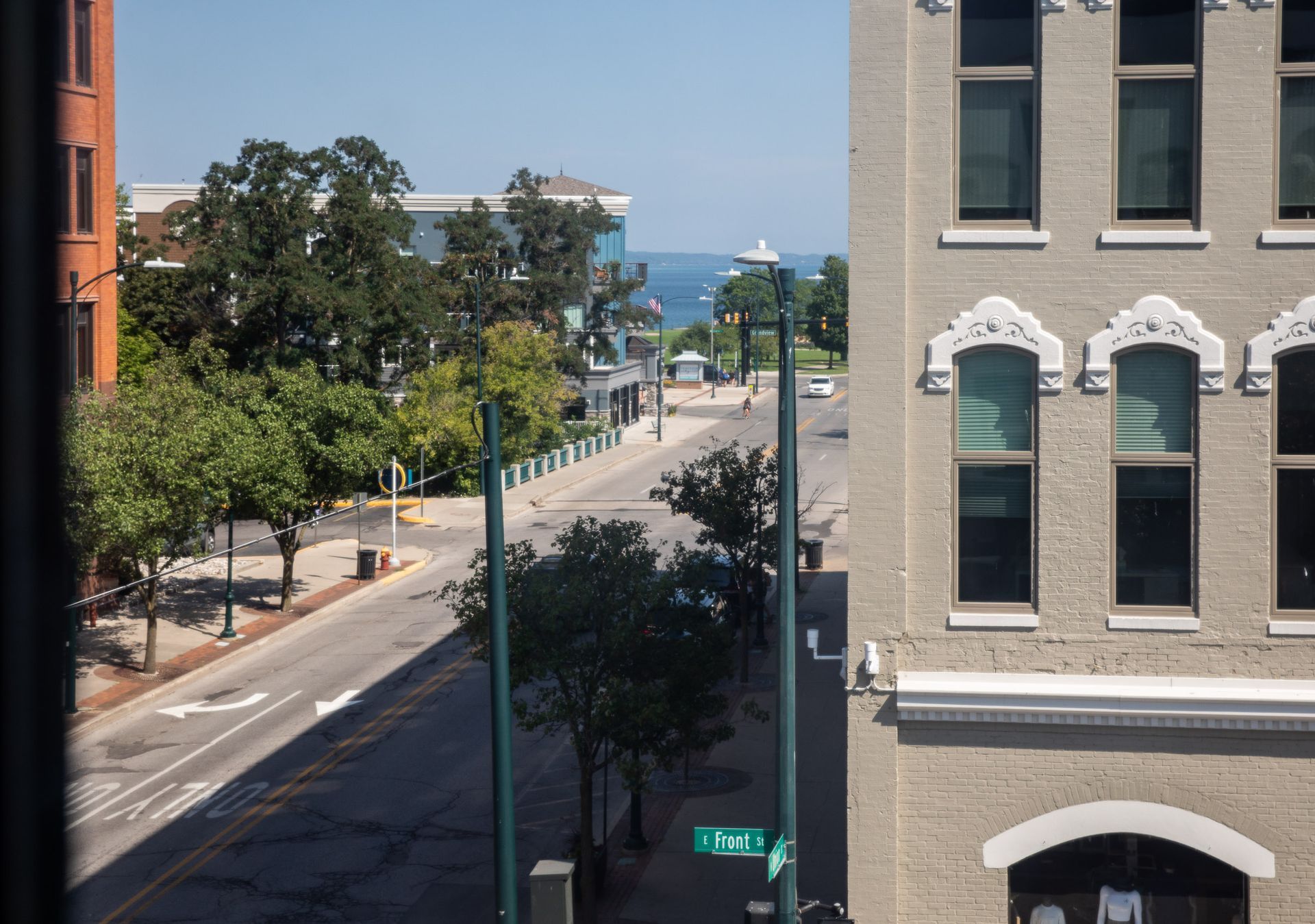 A view of a city street from a window with a green street sign