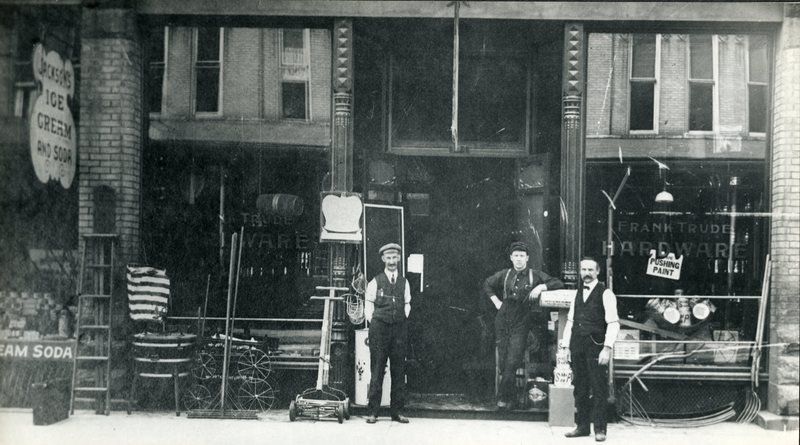 A black and white photo of men standing in front of a building
