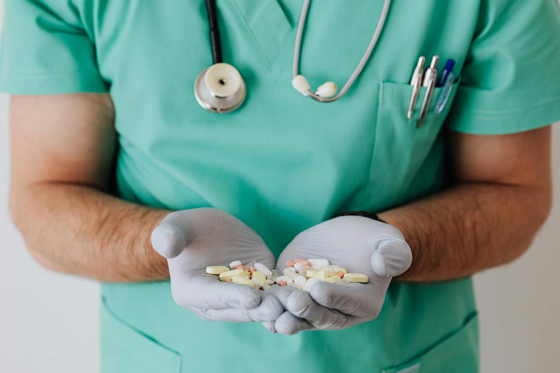 A doctor is holding a bunch of pills in his hands.